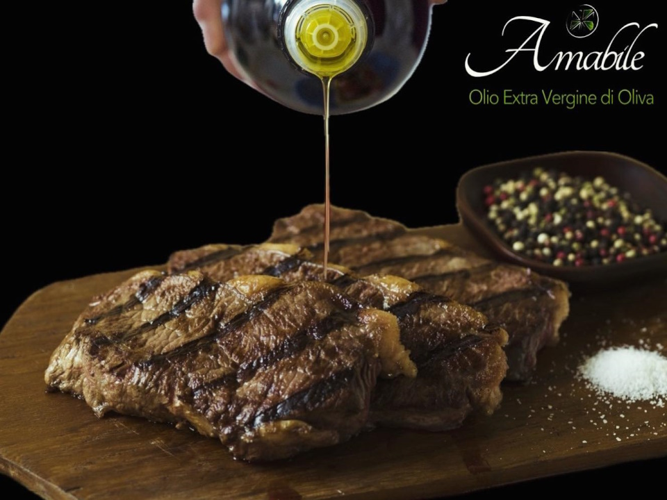 Bottle of Amabile evo oil poured on steak